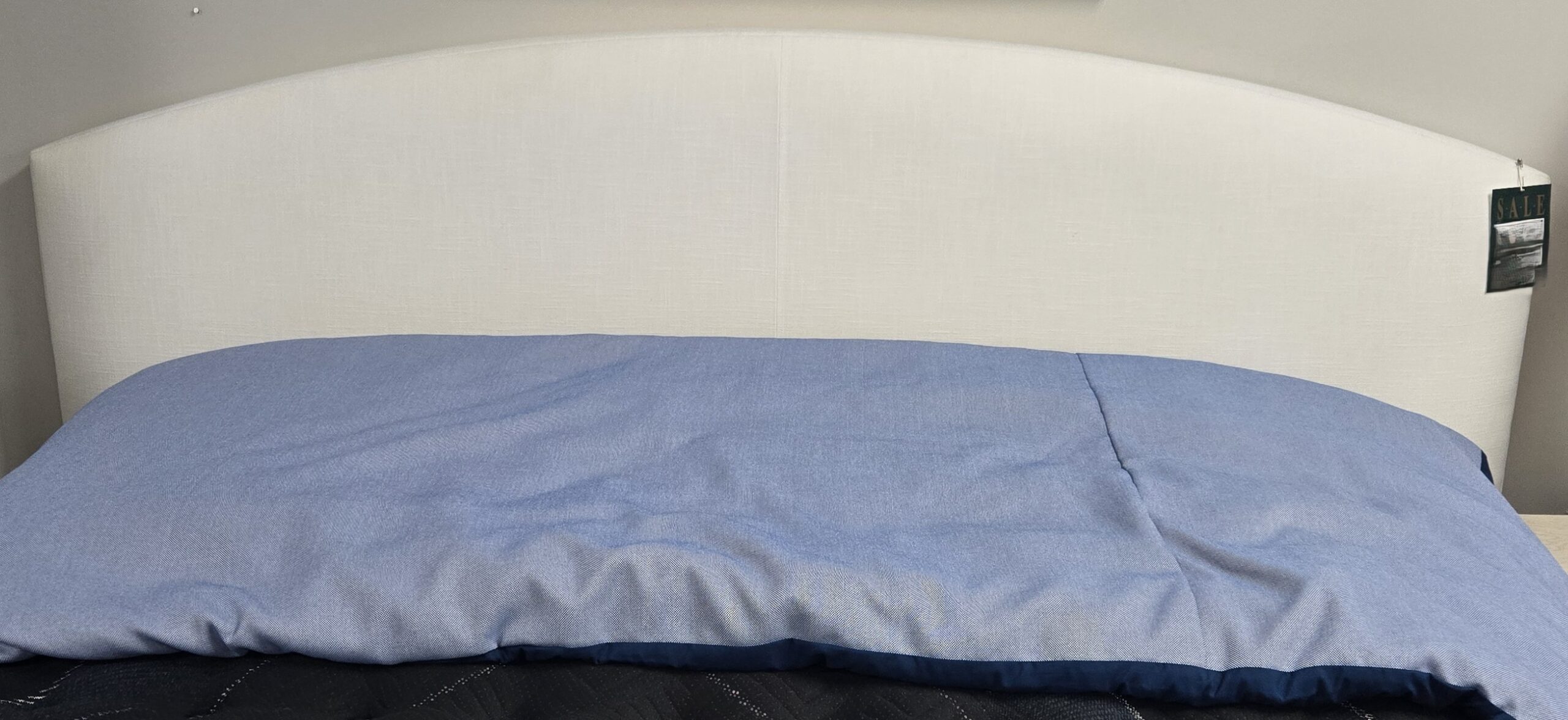 a bed with a blue comforter and a white headboard