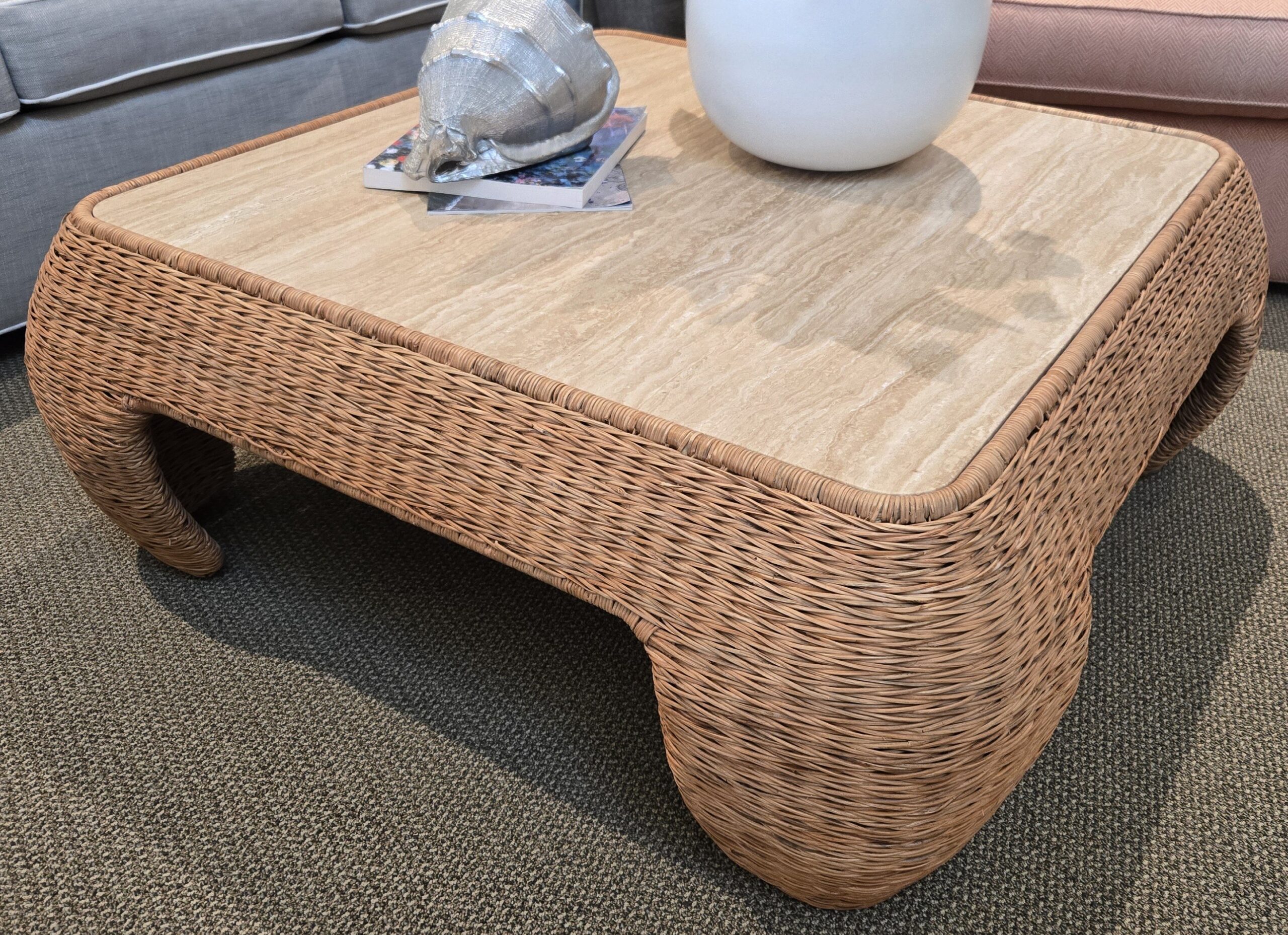 a wicker coffee table with a vase on top