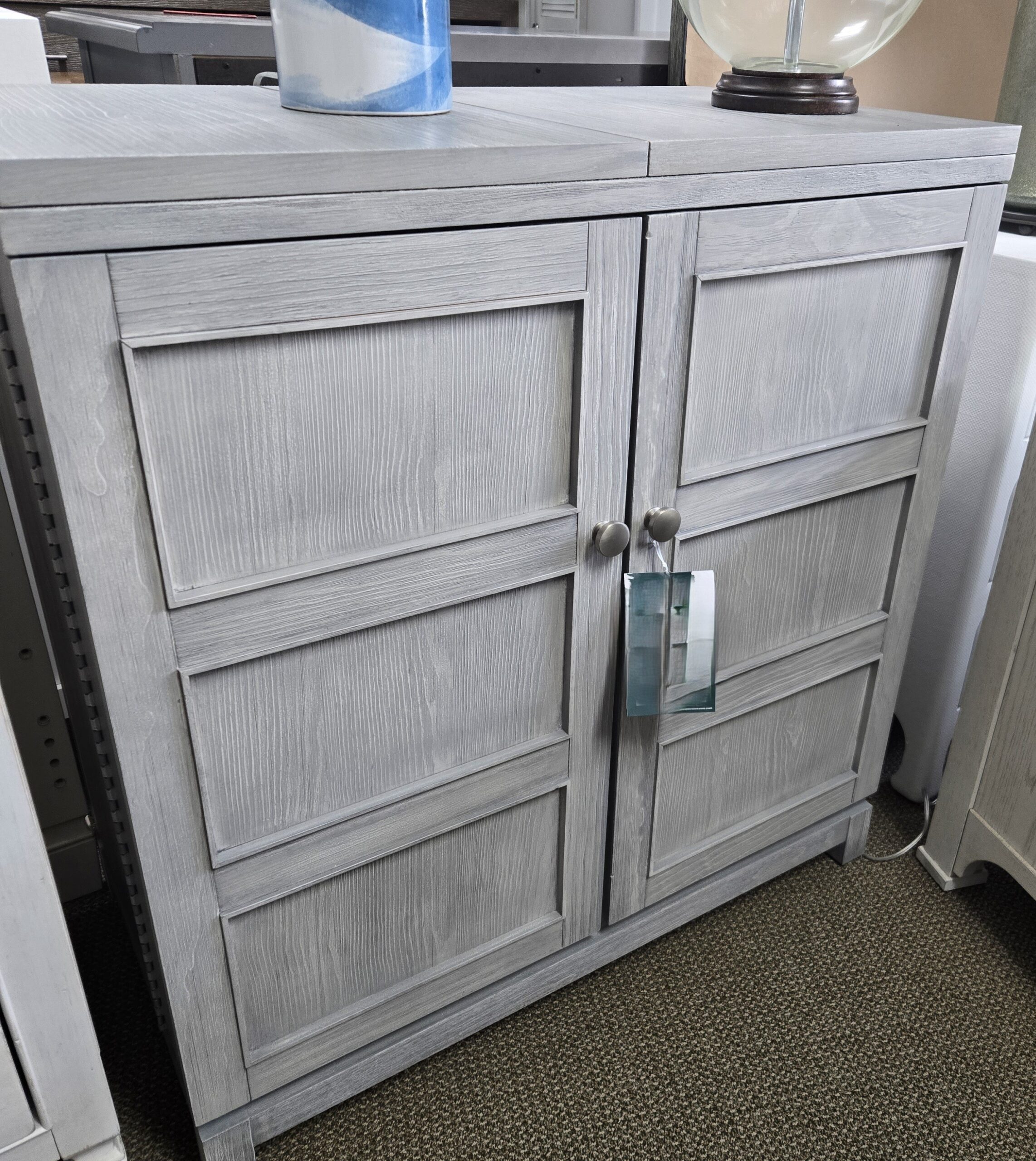 a gray cabinet with a blue vase on top of it