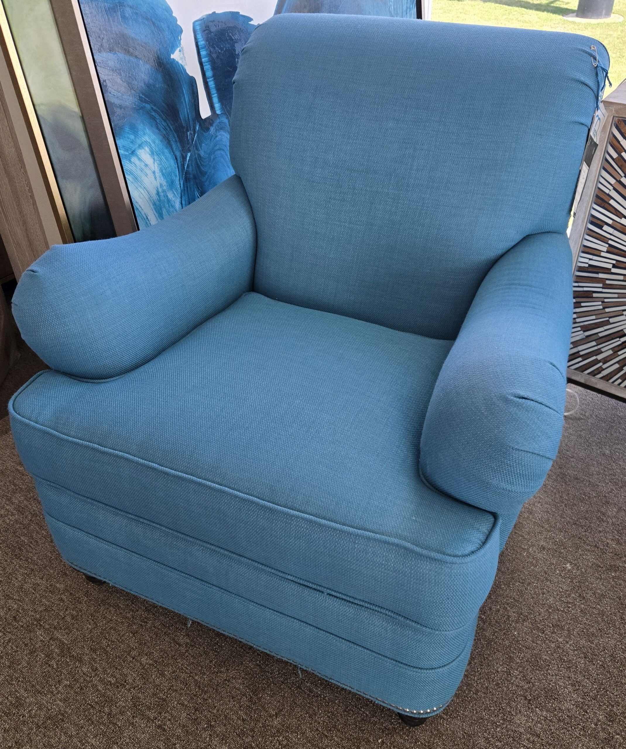 a blue chair sitting in a living room next to a window