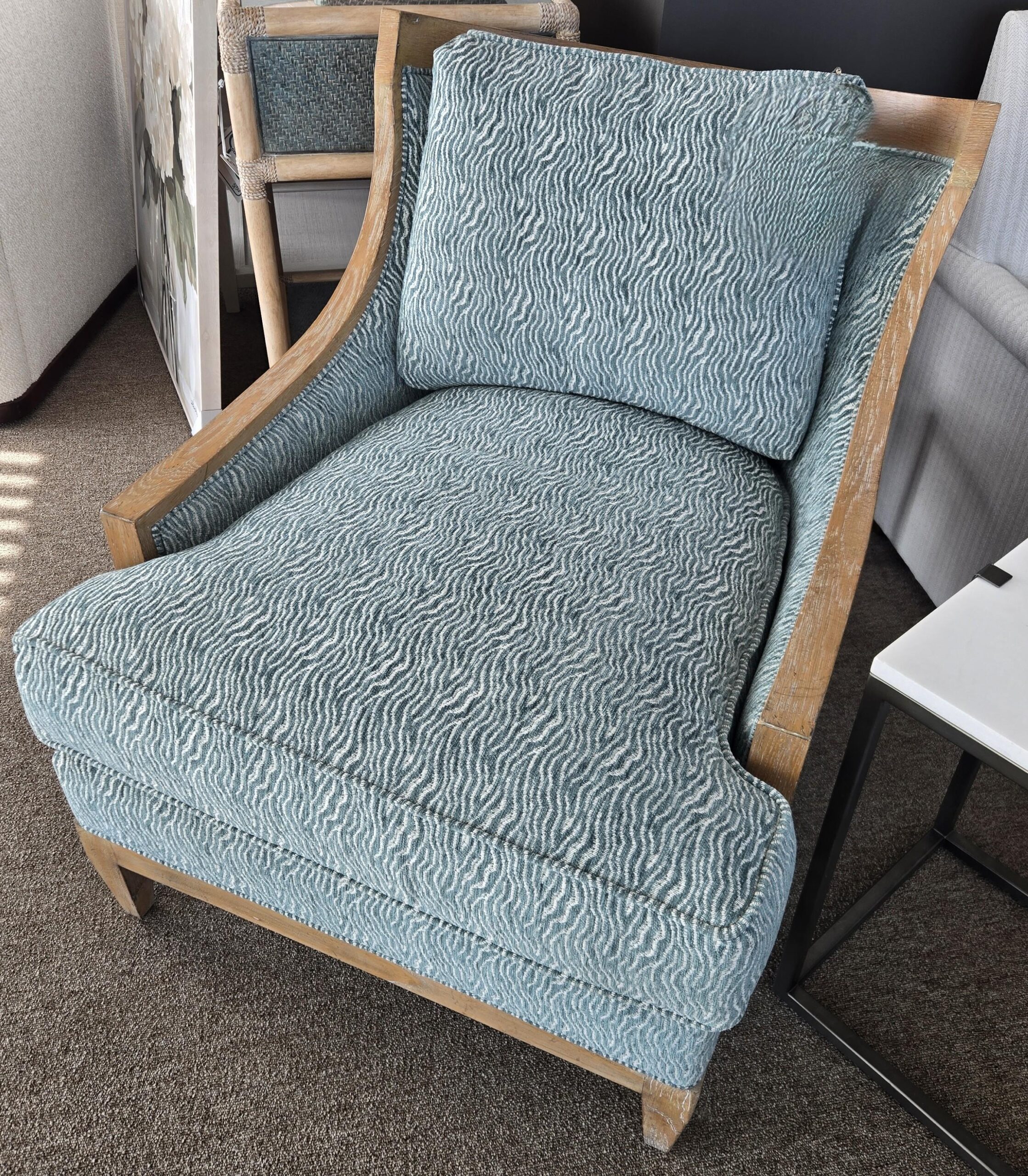 a blue chair sitting in a living room next to a window