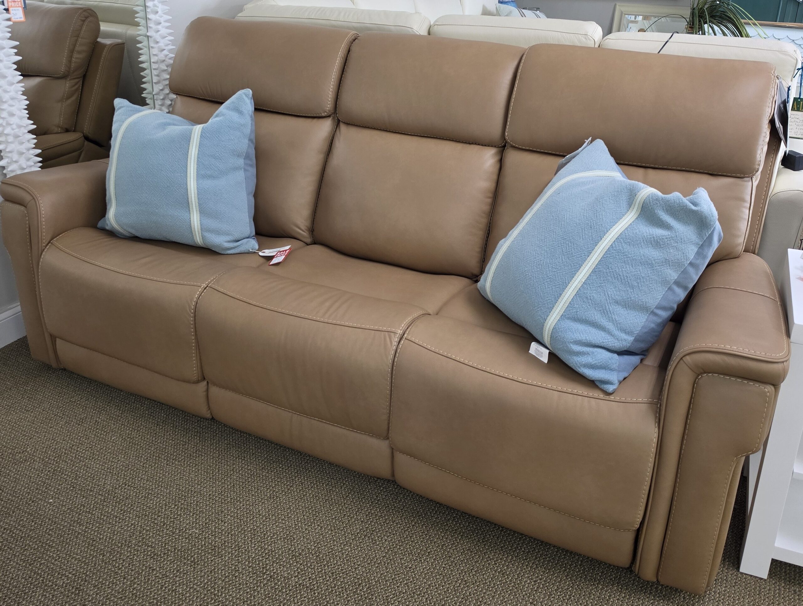 a tan couch with blue and white pillows