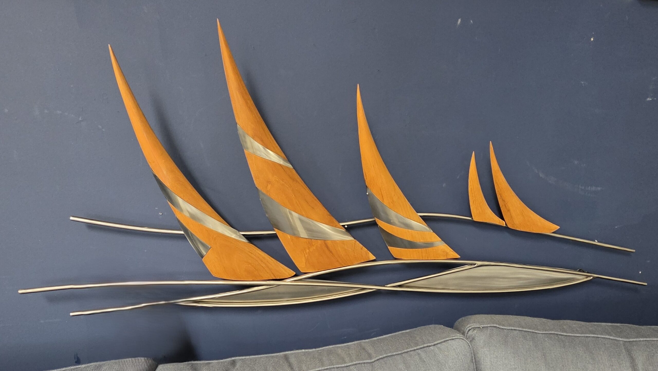 a metal sculpture of a sailboat on a blue wall