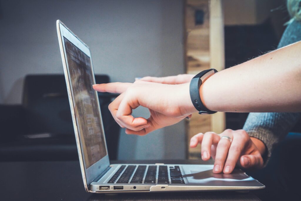 Two people using and pointing at laptop
