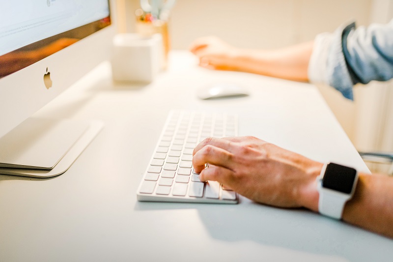 Person typing on apple computer
