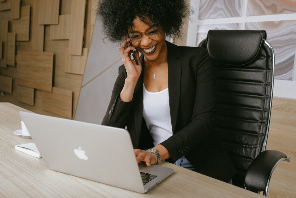 Woman speaking on phone while typing on laptop