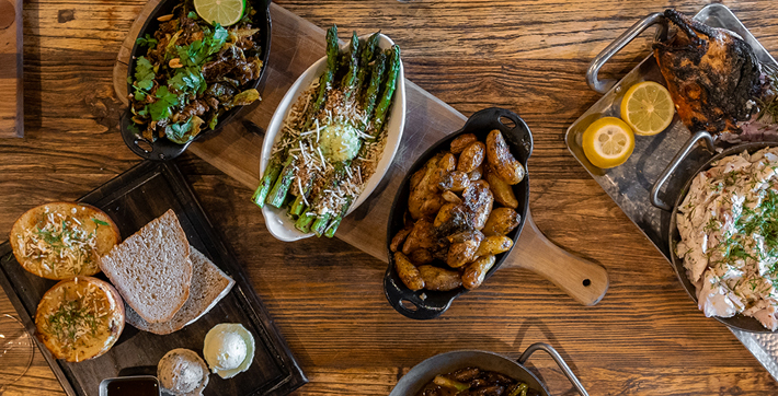 Bread, potatoes, asparagus, chicken, and lemon on wooden boards