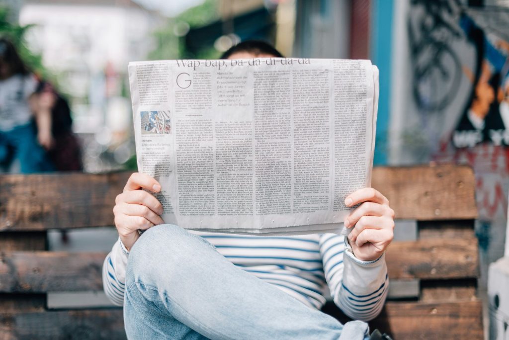 Woman reading newspaper on bench