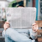 Woman reading newspaper on bench