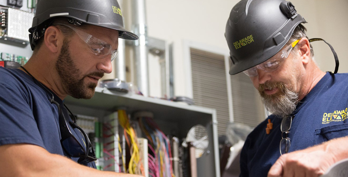 Two DE Elevator employees wearing helmets