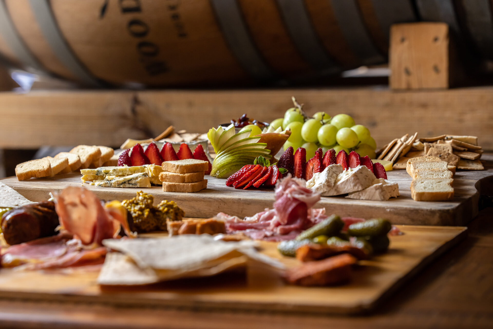 Charcuterie boards with meat, cheese, pickles, strawberries, grapes, pears, sausage, and mustard.