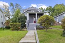A gray house with a concrete walkway up to the front door.