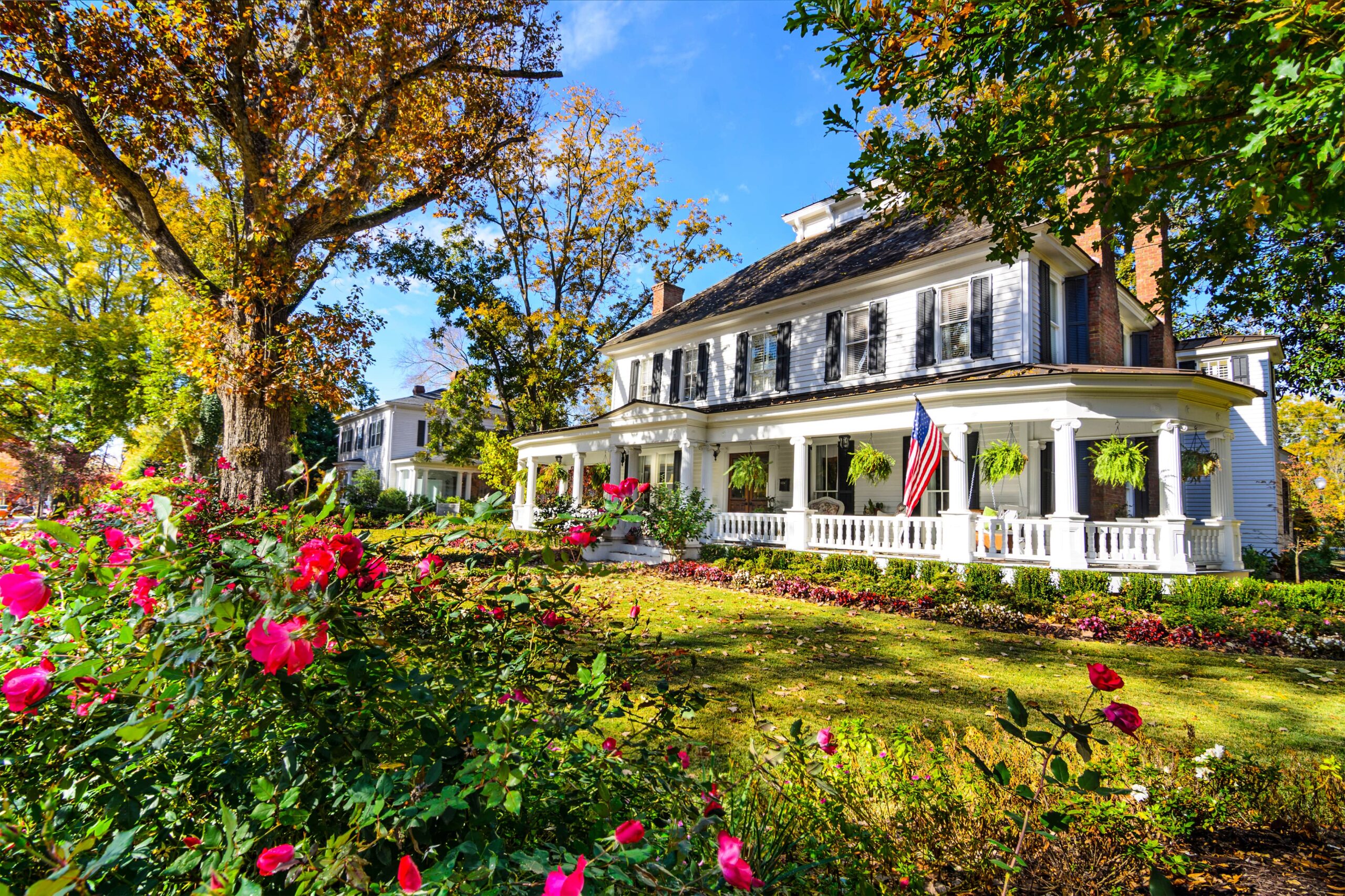 a white house surrounded by flowers and trees