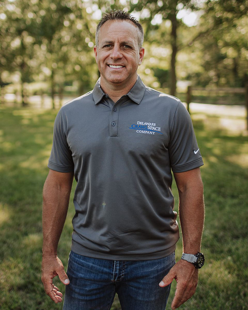 a man standing in the grass with his hands in his pockets