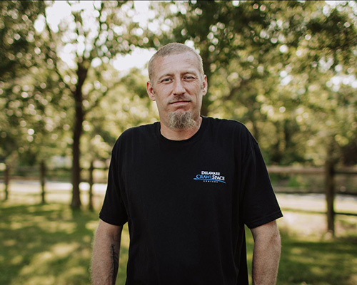 a man standing in a park with trees in the background