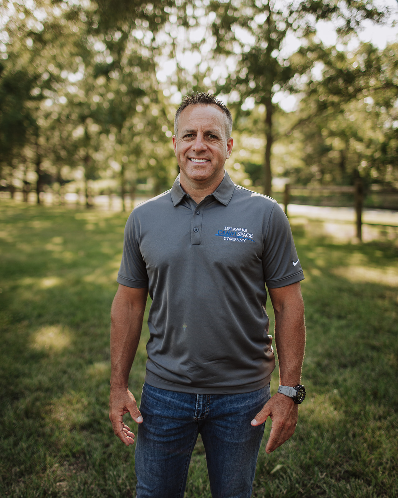 a man standing in a field with trees in the background