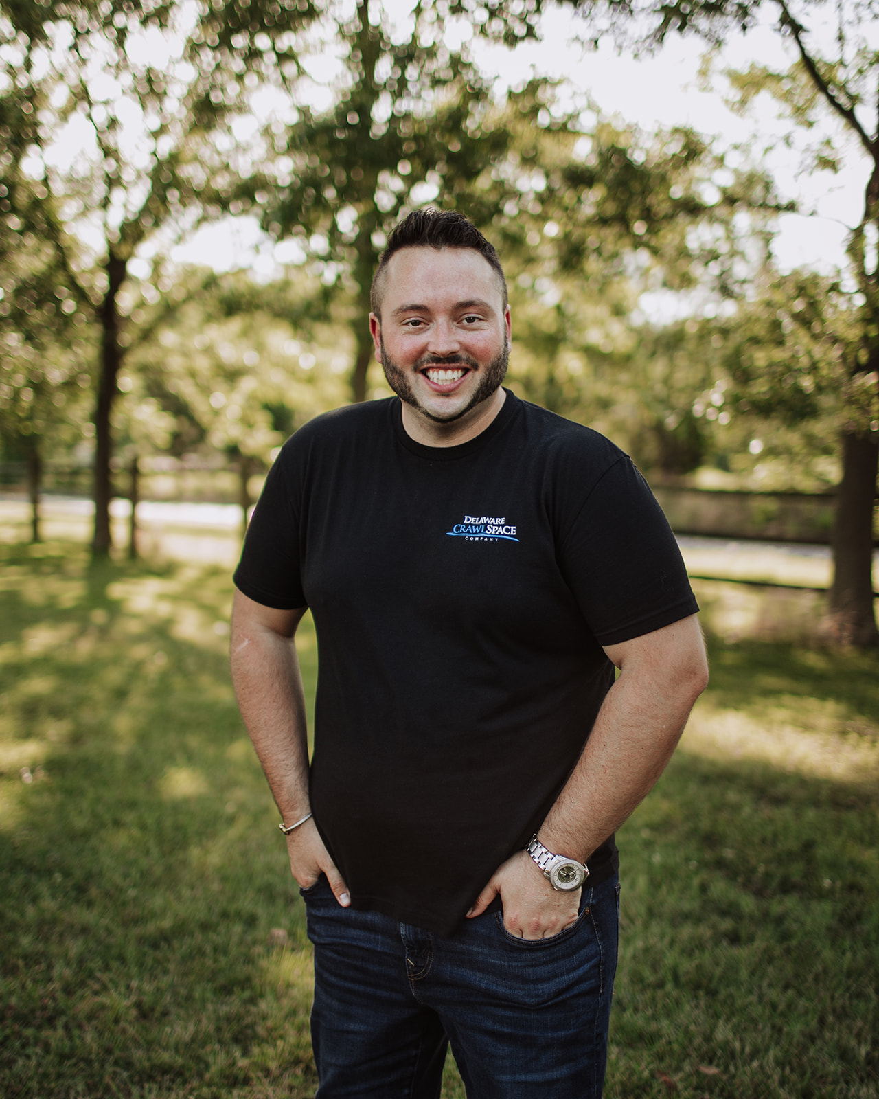 a man standing in the grass with his hands in his pockets