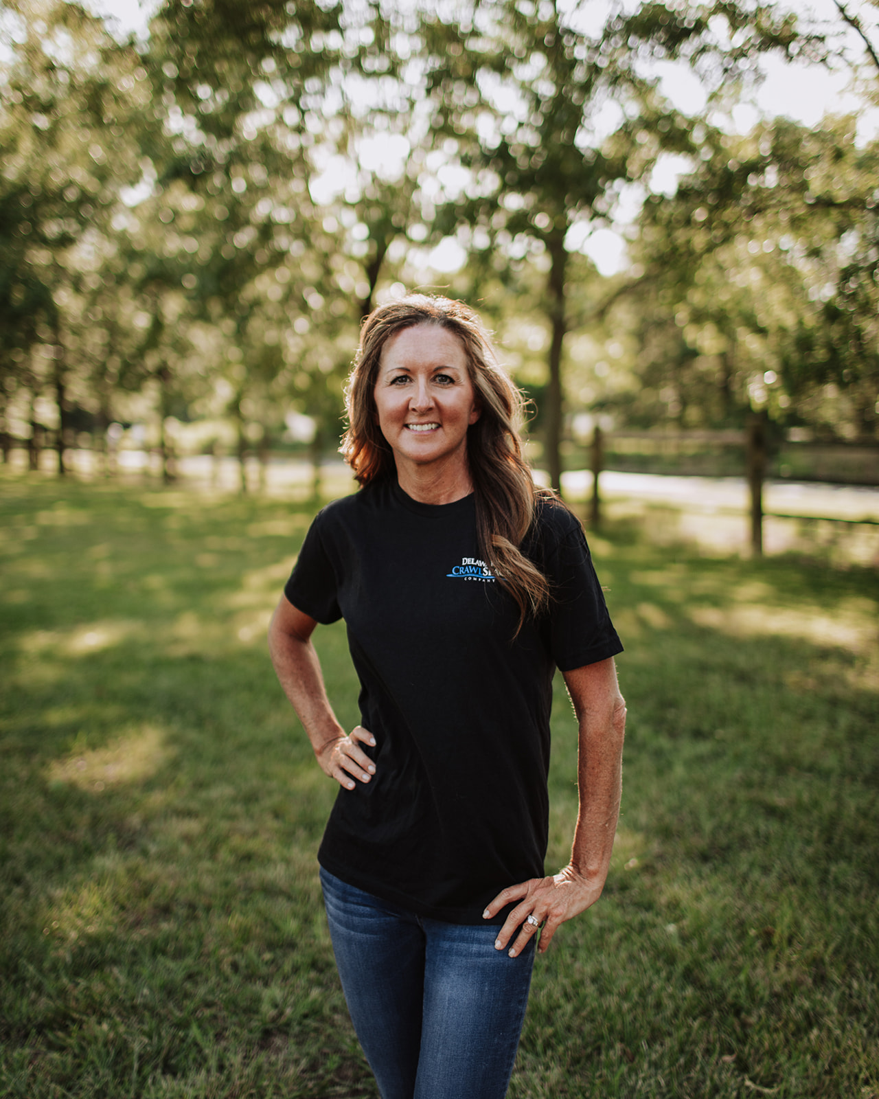 a woman standing in the grass with her hands on her hips