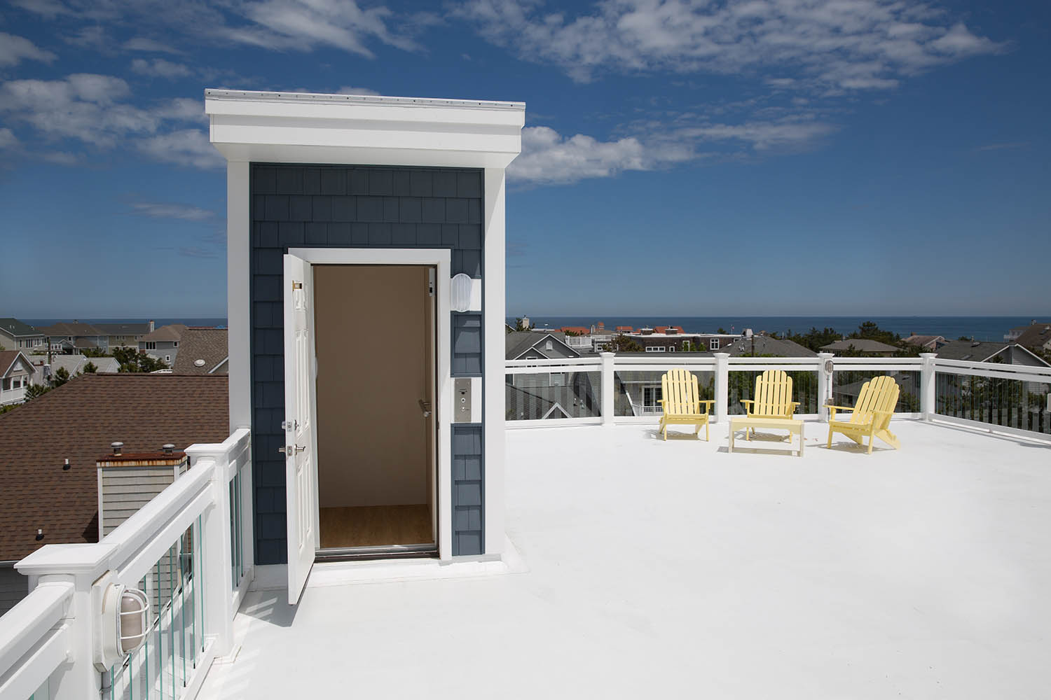a balcony with chairs and a door leading to the ocean