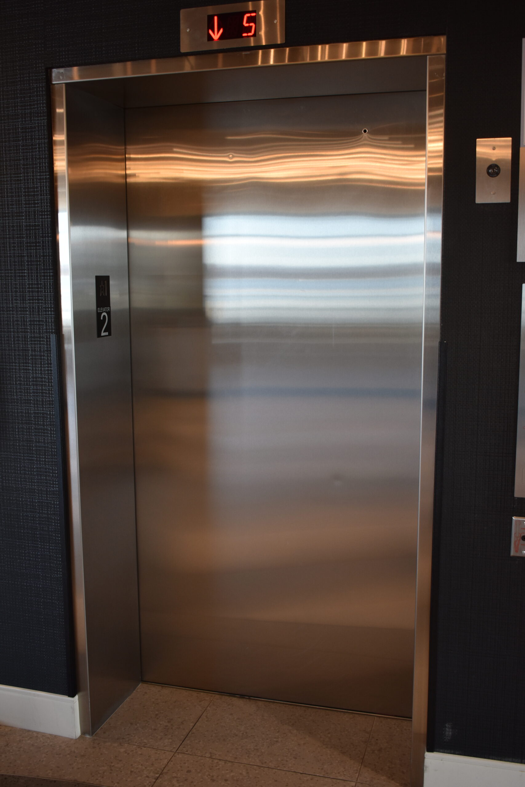 a stainless steel elevator with a clock on the wall