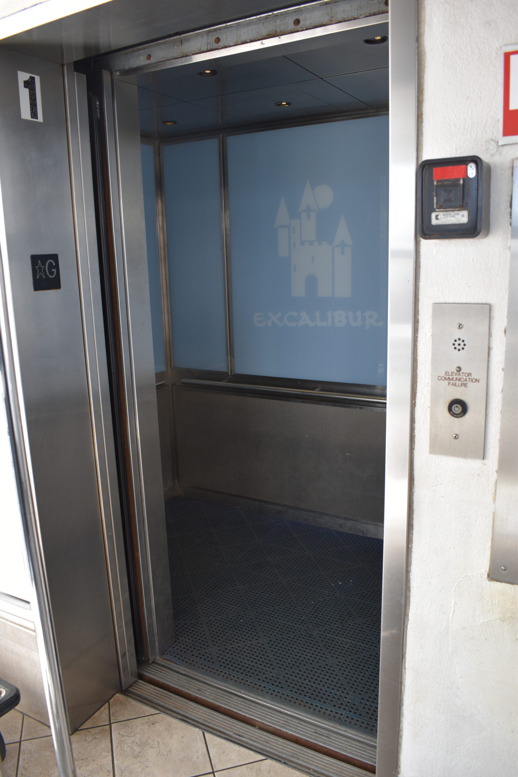 a stainless steel elevator with a glass door