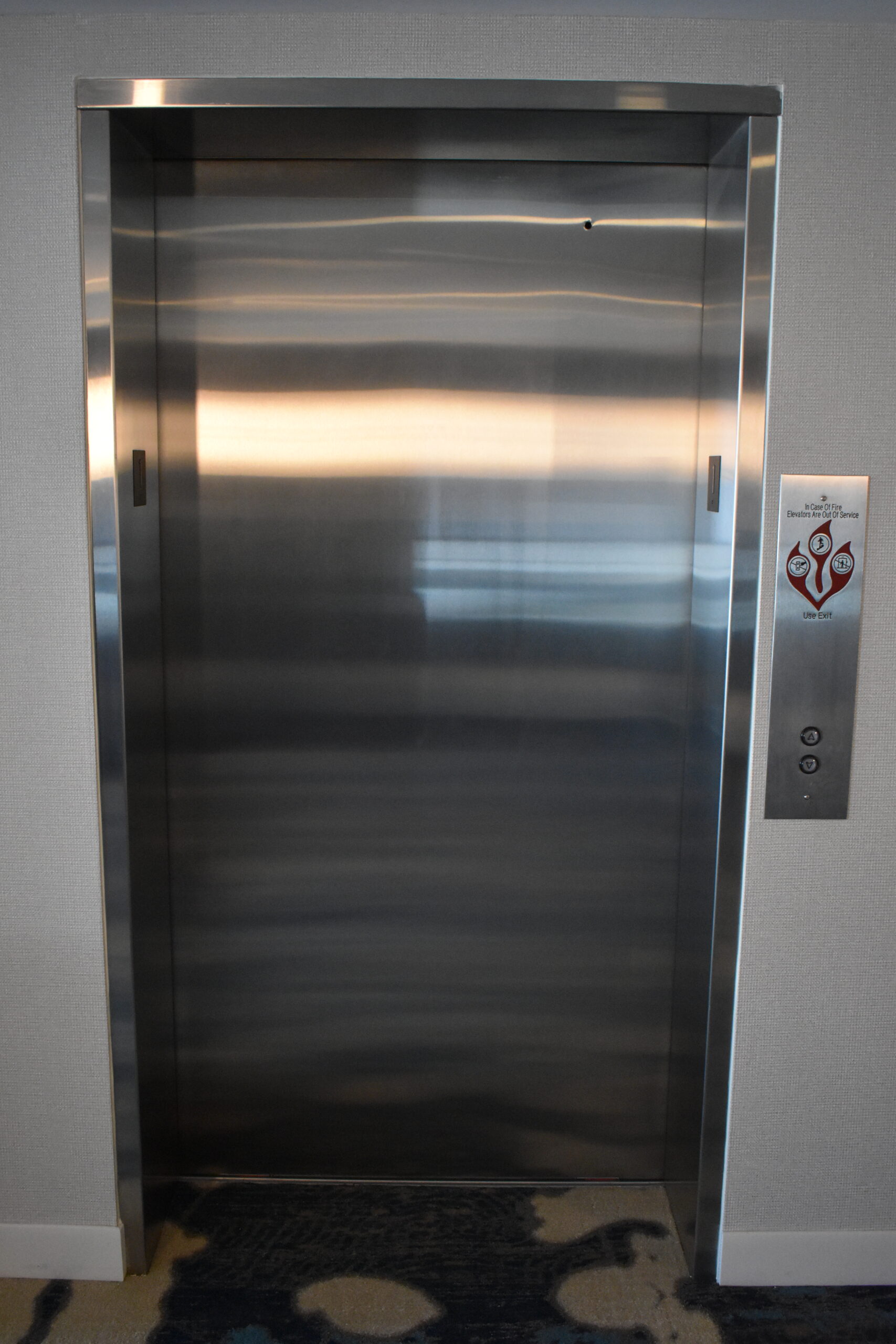 a stainless steel elevator with a blue carpet