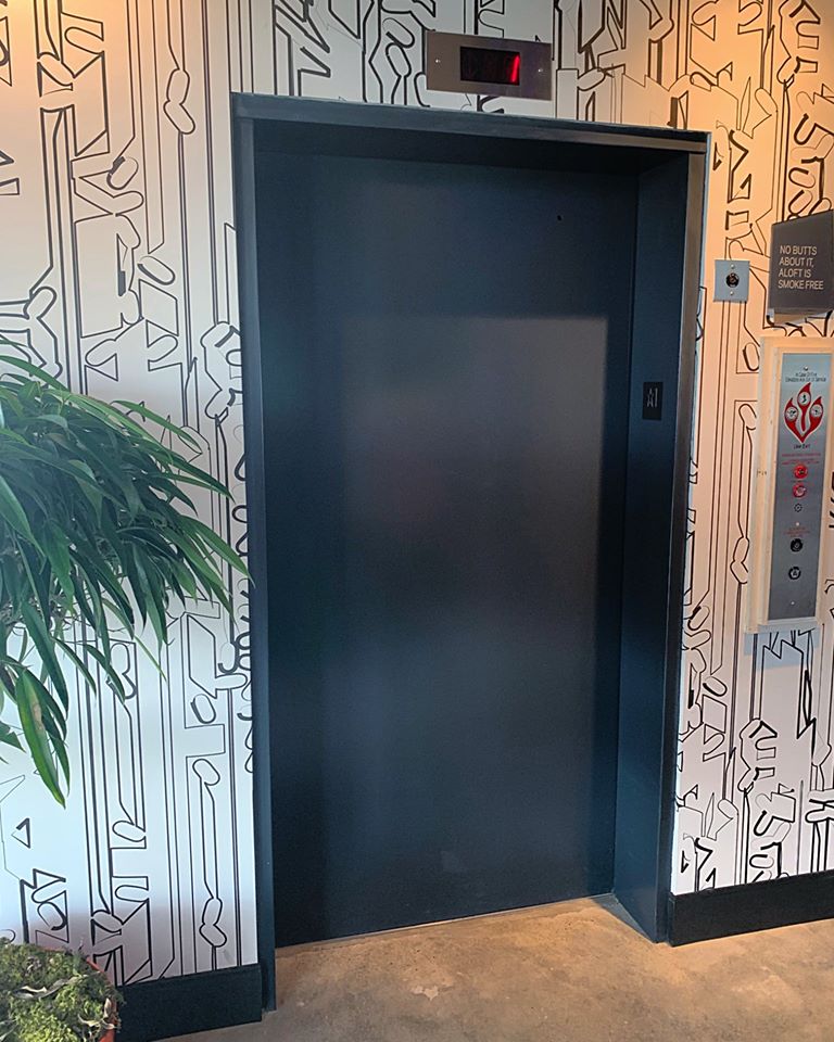 a black and white wall with a black door and a plant