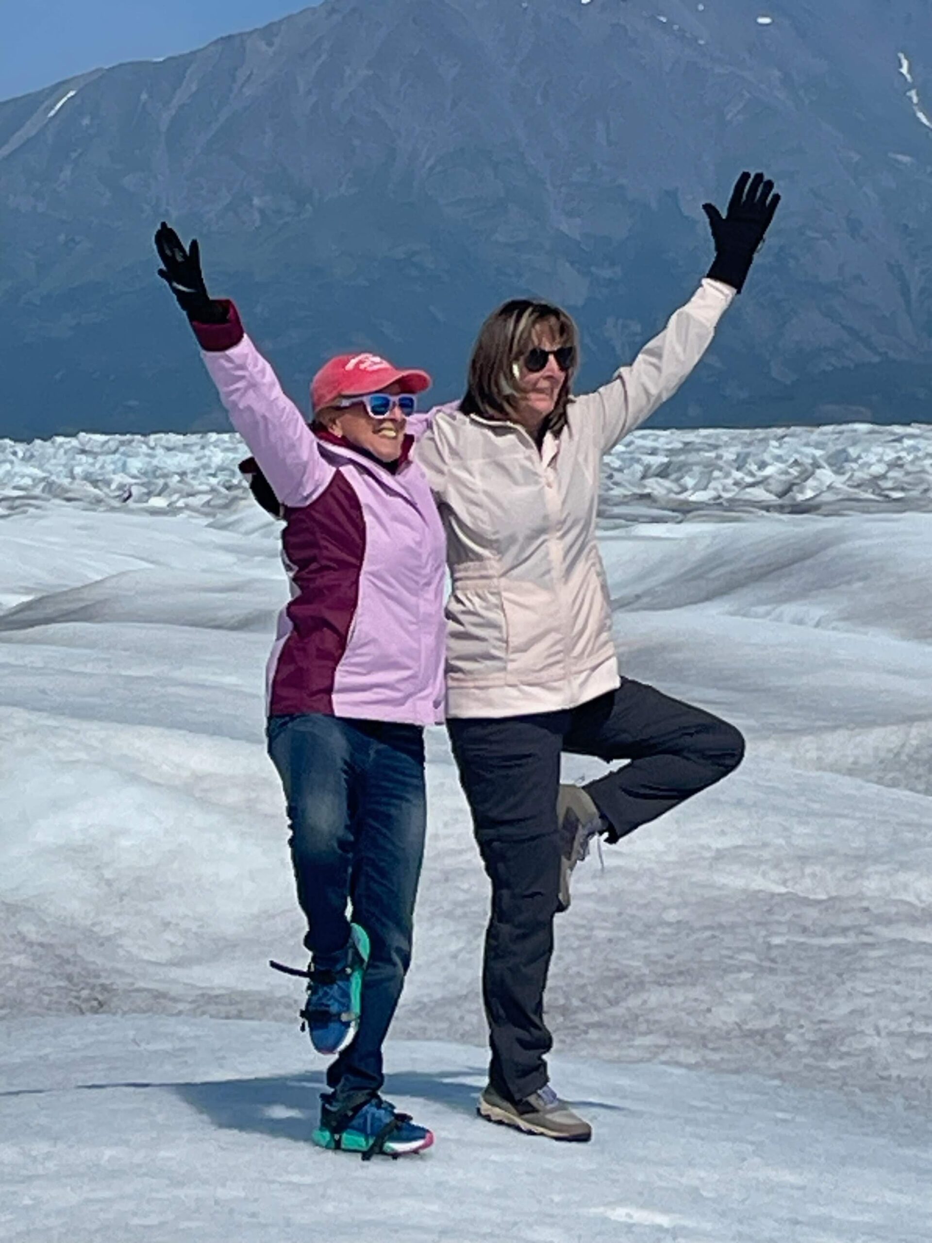 Two women holding a yoga pose on a snowy mountain.