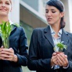 Two women in pantsuit holding plants