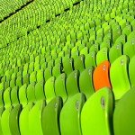 Bleachers filled with green chairs and one orange chair stands out