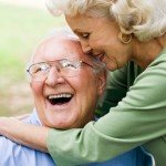 An eldery couple embrace in a hug with big smiles