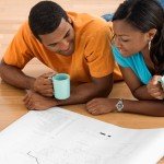 Couple lay on floor drinking coffee looking and paper
