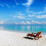 Lone beach chair sits on white sand