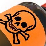 A brown bottle with orange label of skull and bones