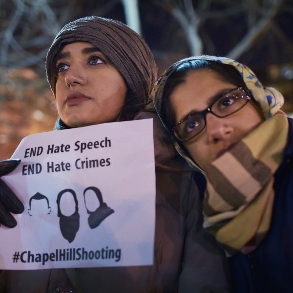 Two woman huddle in the cold at vigil for the Chapel Hill shooting