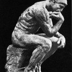 Stone statue of The Thinker with black background