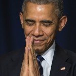 Obama holds hands in prayer with eyes closed and a smile