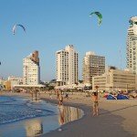 Beacn goers fly kites with hotels/motels in background