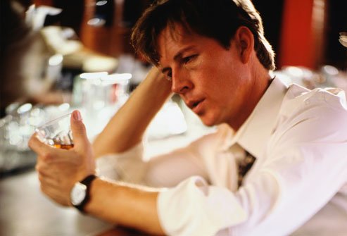 Man holds glass of alcohol sitting at the bar