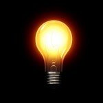 Lit up yellow-ish light bulb on a black background
