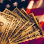 US money fanned out with American flag in the background