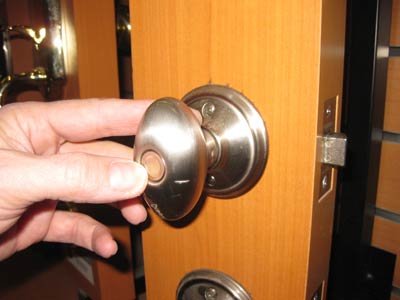 Hand reaches out to open wooden door with silver doorknob