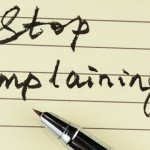 Lined notebook paper and pen with words Stop complaining!