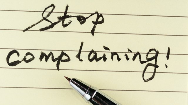 Lined notebook paper and pen with words Stop complaining!