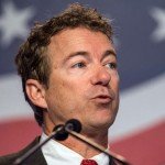 Rand Paul mid-sentence at speaking convention with American flag in background