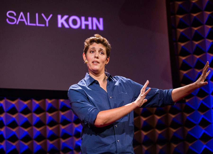 Sally Kohn speaking live with name on TV in background