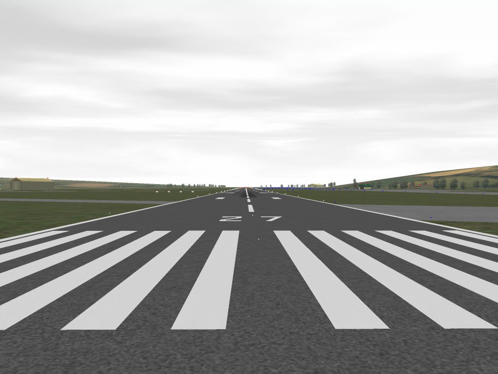 View of an airport runway going into the distance with surrounding green fields