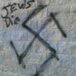 Nazi symbol graffiti on stone wall with words Jews Die