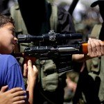 Young boy is shown how to hold rifle
