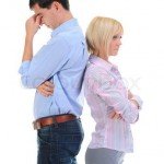 A couple stand back to back with woman's arms crossed